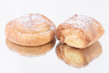 A tasty puff pastry roll and a delicious puff pastry roll with powdered sugar on top