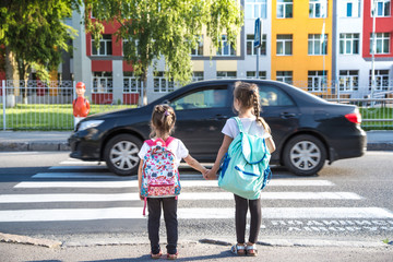 Back to school education concept with girl kids, elementary students, carrying backpacks going to class