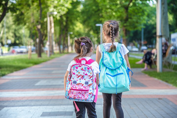 Back to school education concept with girl kids, elementary students, carrying backpacks going to class