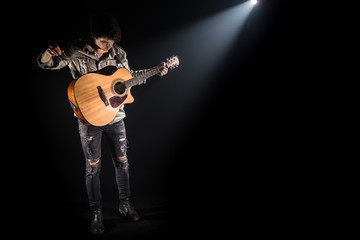 Obraz premium Guitarist, music. A young man plays an acoustic guitar on a black isolated background