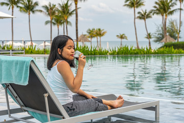 Young woman sipping her wine and relaxing at swimming pool