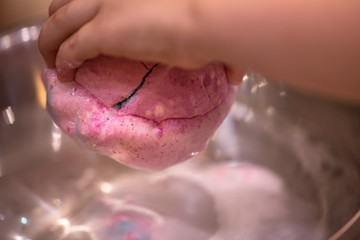 Fototapeta premium Bright natural fizzy bath bomb dissolves in the hands