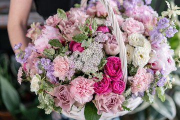 Flower arrangement in Wicker basket. Beautiful bouquet of mixed flowers in woman hand. Floral shop concept . Handsome fresh bouquet. Flowers delivery
