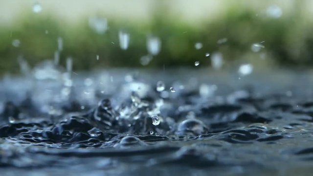 close up rain water drop falling to the water surface in rainy season
