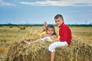 Naklejka na ściany i meble Portrait of brother and sister in the manger . Children on a walk in the countryside . Children's outdoor recreation