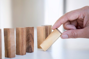 Risk and Strategy in Business, Image of hand gambling placing wooden block on a line of domino,...