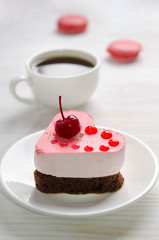 souffle cake in the form of heart  with cup of coffe and macaroons on a wooden table