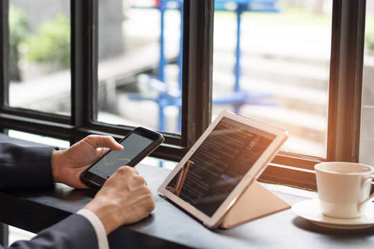 Causal professional Business man using multichannel services with internet wifi 5G on smartphone and online tablet in coffee shop.City lifestyle businessman hands working using mobile phone concept