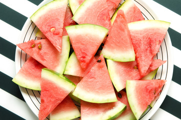 Fresh red watermelon slice in plate on striped background. Summer concept. Top view, Flat lay. - Image