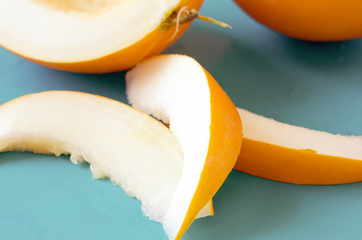 Yellow honeydew melon half with seeds and slices on blue background. - Image