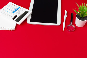 Red office desk table with blank notebook, keyboard and supplies. Top view with copy space. Flat lay.