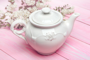 White ceramic tea kettle on wooden table close up