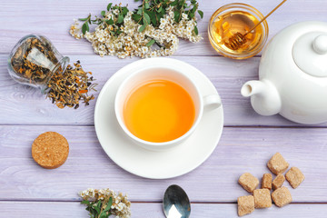 Cup of tea with sugar cubes and flower branches on wooden table close up