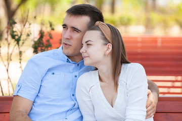 Obraz premium Young couple sitting on bench in park.