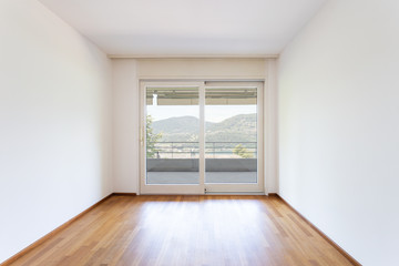 Bedroom with white walls and parquet. Window with lake view.