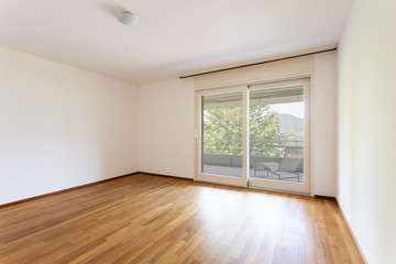 Bedroom with white walls and parquet. Window with lake view.