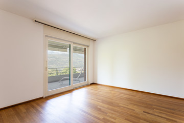 Bedroom with white walls and parquet. Window with lake view.
