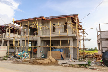 Fototapeta premium construction residential new house in progress at building site with clouds and blue sky