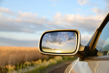 Sunset sky reflect in rearview mirror of car. - 279089045