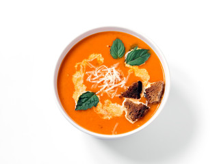 Traditional homemade tomato soup with basil leaf top view on a white background