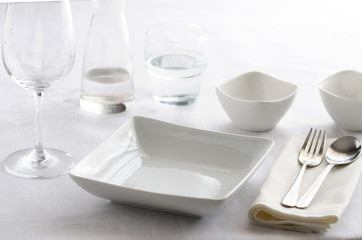 Table setting white and grey colour. Empty glasses and plates set with napkin and cutlery. Restaurant interior background...