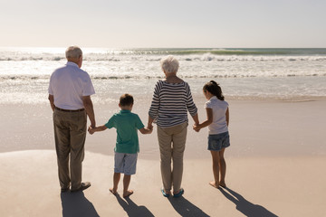 Family holding hands and standing on beach 