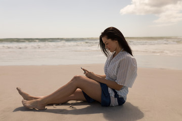 Fototapeta na wymiar Beautiful young woman using mobile phone at beach