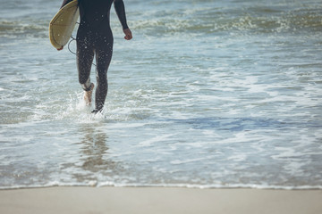 Male surfer with a surfboard walking on a beach