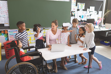 Schoolgirl using virtual reality headset at school in classroom