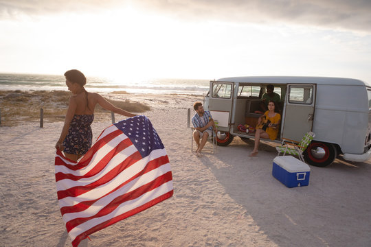 Mixed-race woman holding an American flag against his friends in background
