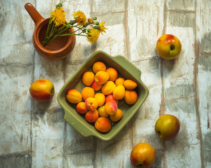 Set of fruit nectarine and apricot in a green square plate on a light table, shot from the top...
