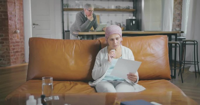 Senior woman suffering from cancer looks concerned and examines prescriptions