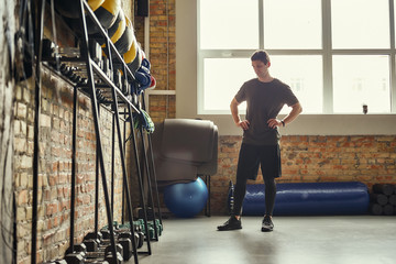 Ready for workout. Confident young man is looking at sport equipment while exercising at gym.