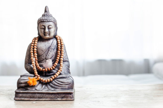 Buddha statue with beads. Buddha statue in bright room.