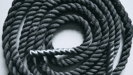 Close up of black battle rope on a gray backgound. Sport and fitness equipment. Functional training