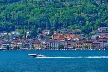 The yacht of dark color at high speed moves against the backdrop of the resort town in Italy