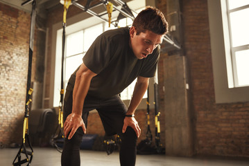 Just a minute to rest. Young athletic man in sportswear looking exhausted while standing at gym