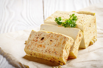 Soy Bean curd tofu on parchment paper with greens Non-dairy alternative substitute for cheese