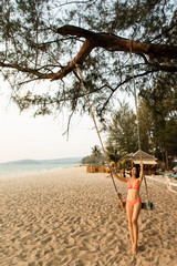 Girl sitting on the swing on the tropical beach, paradise island. Beautiful girl on a beach 