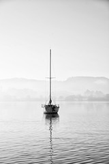 Stunning unplugged fine art landscape image of sailing yacht sitting still in calm lake water in...
