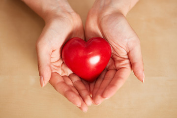 Woman holds red heart in hands as a care concept
