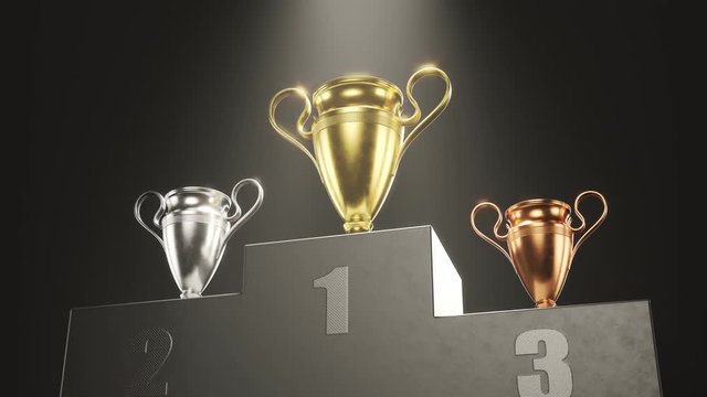 Golden, silver and bronze metallic trophy cups on a podium in the spotlight 4KHD