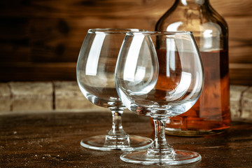 A bottle of cognac and glass on a brown wooden background. Brandy