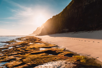 Tropical sandy beach with rocks and sunshine in Bali