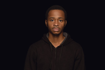 Close up portrait of young african-american man isolated on black studio background. Real emotions...