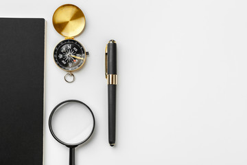Golden compass with black notepad and pen close up on a table