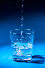 Close up pouring purified fresh drink water from the bottle on table