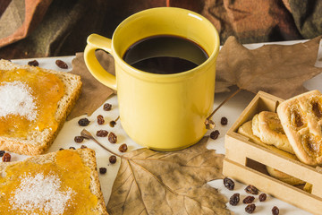 Desserts and leaves near mug of coffee