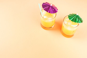 Summer orange ananas cocktails with neon color umbrellas. Vacation on the beach concept on orange bright background.