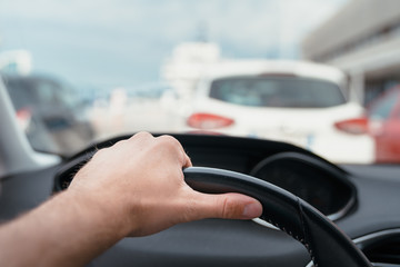 A man's hand on steering wheel patiently waiting in queue